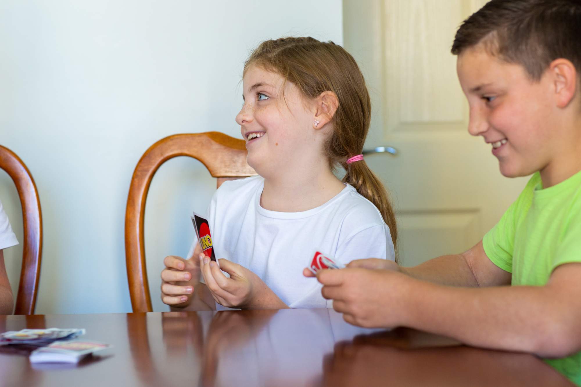 A young girl playing Uno with her sibling